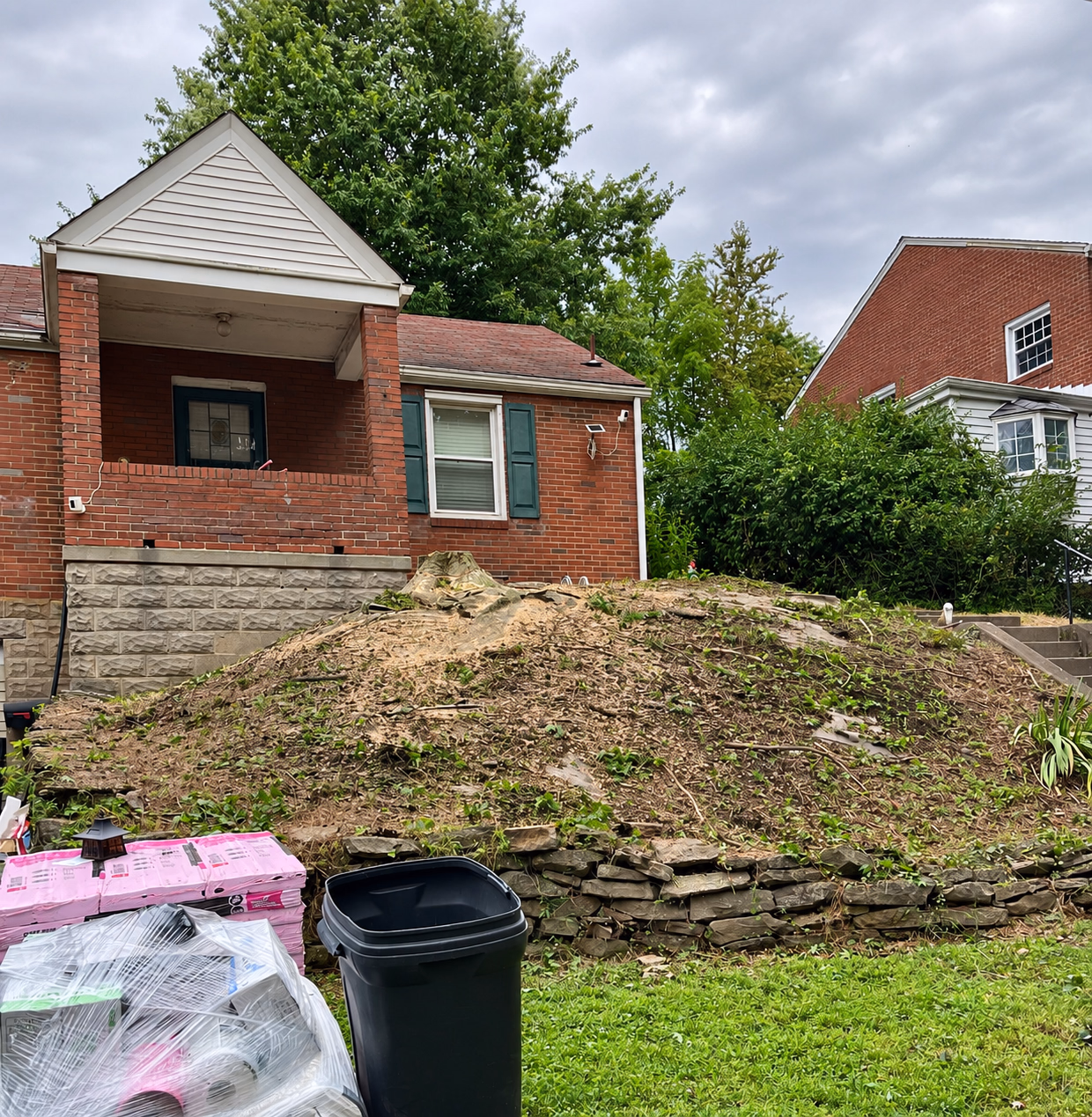 After: the mound in front of the brick house with the tree removed.